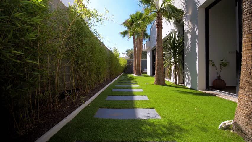 POV shot of a stone walkway with palm trees in a French villas garden