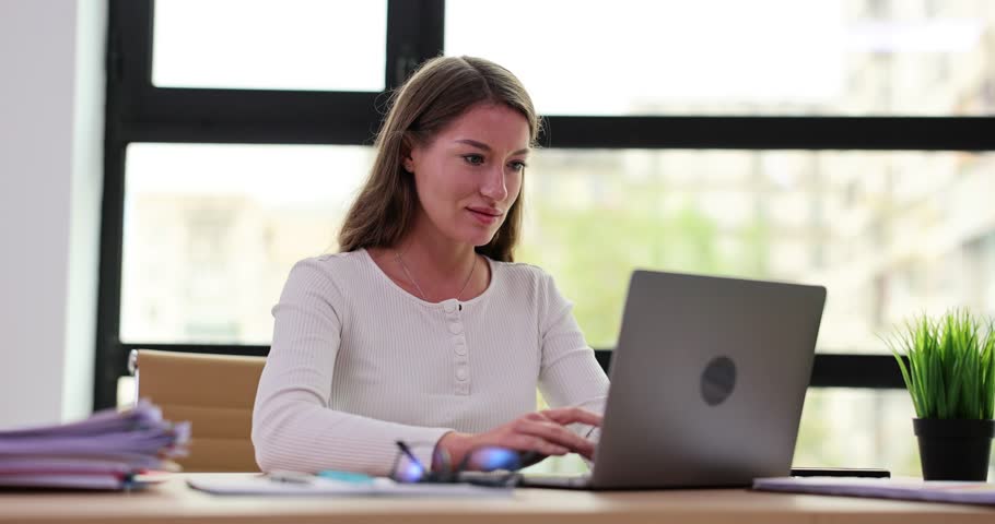 Young beautiful smiling woman working on laptop in office. Manager secretary at workplace