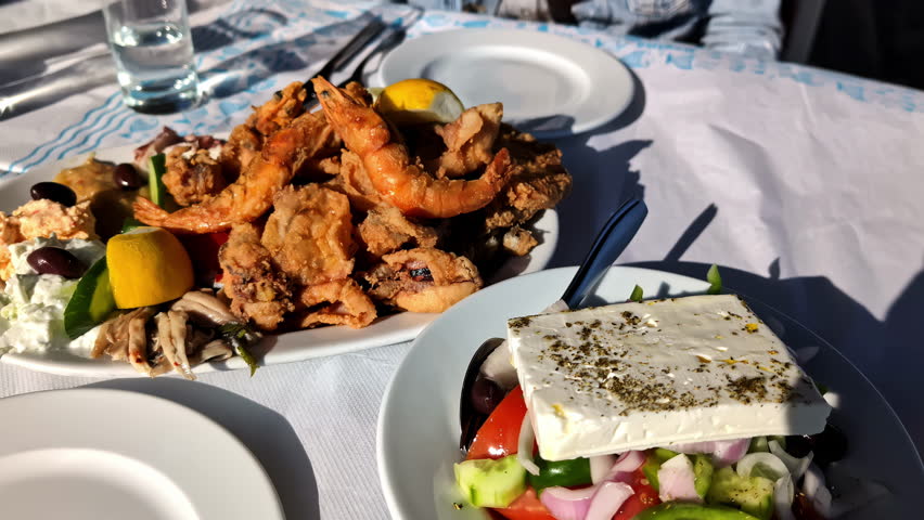 Delicious Seafood and Greek salad served and ready to eat. Close up.