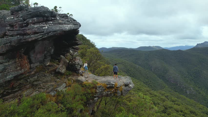 4k Camera video of a girl running towards a boy on the Balconies view point at the Grampians National Park in Victoria, Australia. The couple enjoy the green landcapes and beautiful mountain views.