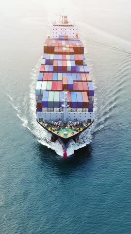 Front of Cargo container ship carrying container and running out international container port customs shipyard sea port concept smart logistic service. Portrait video Container Ship.

