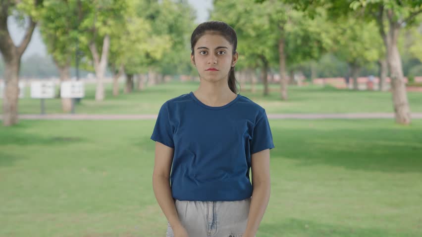 Confident Indian teenage girl standing crossed hands in park