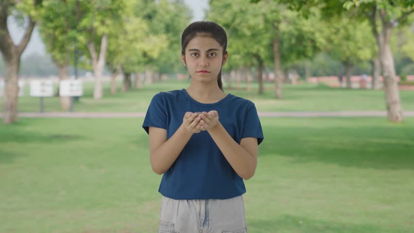 Indian teenage girl holding lot of coins in park