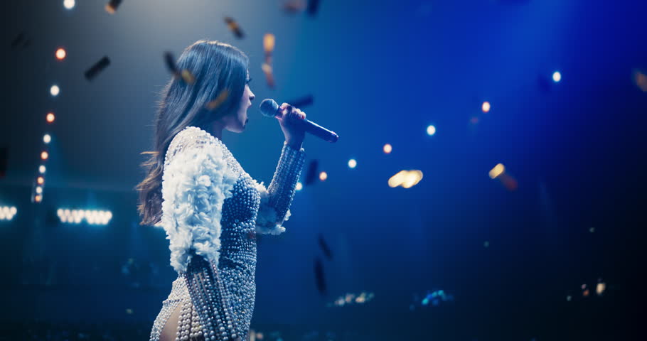 Portrait of a Female Artist Passionately Performing an Emotional Song on Stage. Musician Wearing a Creative Outfit, Holding a Microphone, Glittering Confetti Falling Down, Reflecting Dramatic Lights