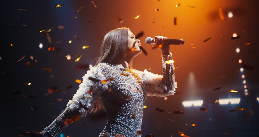 Portrait of a Female Artist Passionately Performing an Emotional Song on Stage. Musician Wearing a Creative Outfit, Holding a Microphone, Glittering Confetti Falling Down, Reflecting Dramatic Lights