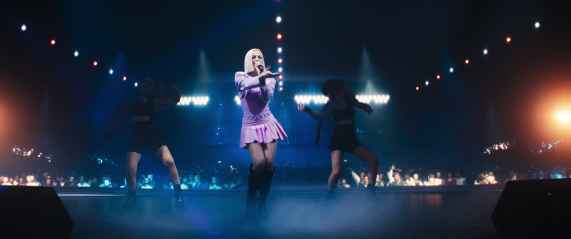 Empowering Girl Band Performing at a Concert Live on Stage. Talented Lead Singer Dancing with a Microphone and Singing Energetic Lyrics, Two Young Athletic Female Dance in Between. Anamorphic Shot