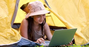 asian woman lying using laptop while they having camping in morning. 4k video
