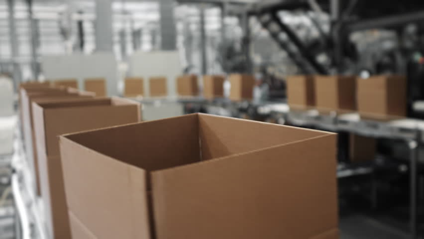 Open cardboard boxes moving along an automated packaging conveyor line in a modern factory, showing industrial logistics, automation and high speed production workflow.
