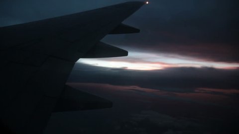 Plane window view - airplane wing on sunset background