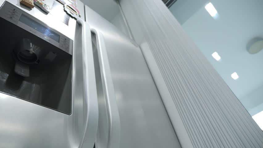 Woman putting a jug of water in the fridge in slow motion. Low angle