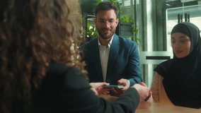 Arabian muslim couple man woman in hijab clients tourists family travel traveling holidays happy guests arrive booking hotel service reception female concierge giving key card passports registration - Powered by Shutterstock - Get 15% off with code: PIKWIZARD15