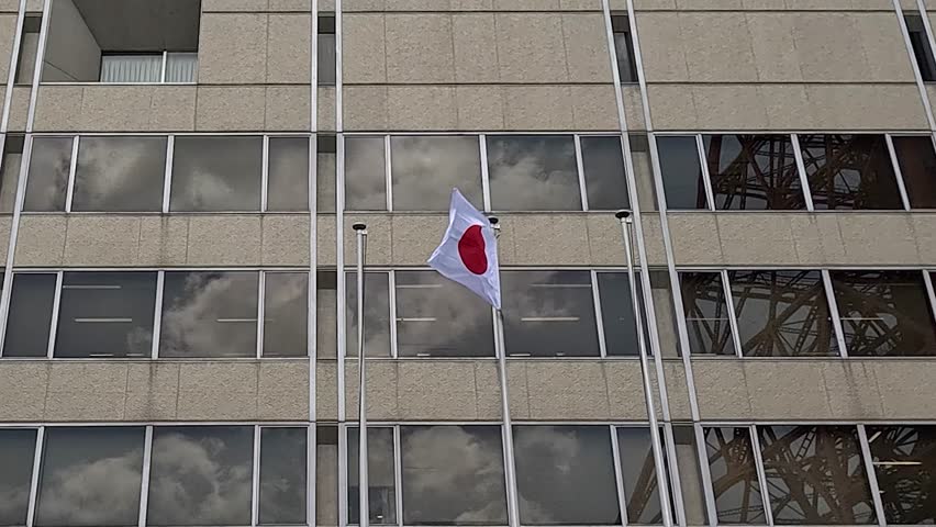 National Flag Of Japan Waving On Glass Facade Of Modern Building. low angle shot