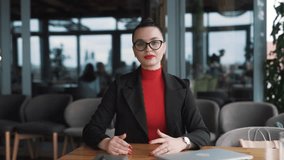 stern young woman in business attire angrily gestures with her hands and argues, looking into the camera while sitting in a stylish restaurant - Powered by Shutterstock - Get 15% off with code: PIKWIZARD15