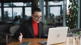 beautiful, stern young woman in business attire argues and gestures with her hands during a video call on a laptop, sitting in an office - Powered by Shutterstock - Get 15% off with code: PIKWIZARD15