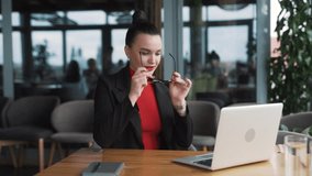stern young woman in business attire argues and gestures with her hands during a video call on a laptop, sitting in an office - Powered by Shutterstock - Get 15% off with code: PIKWIZARD15