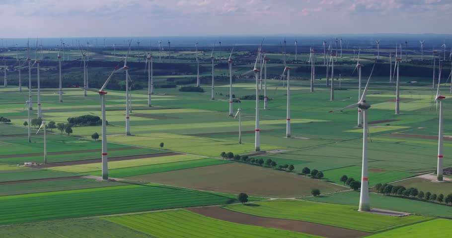 Drone flyby of a large wind farm with wind turbines in motion in the evening