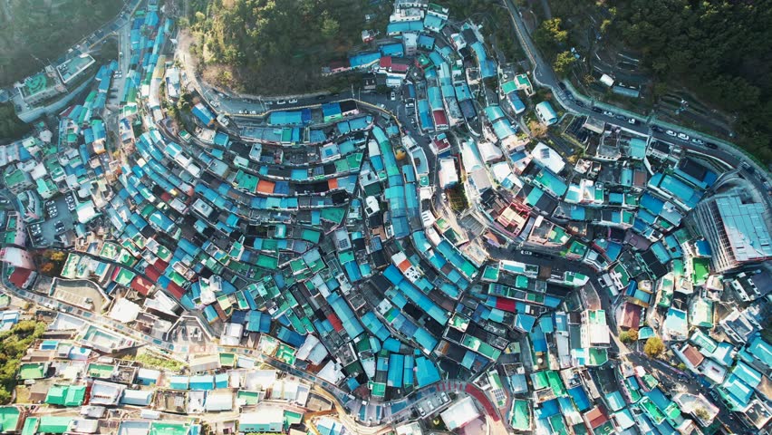 an aerial view of Gamcheon Culture Village in Busan, Korea. It showcases colorful houses densely packed on steep hills with winding roads.