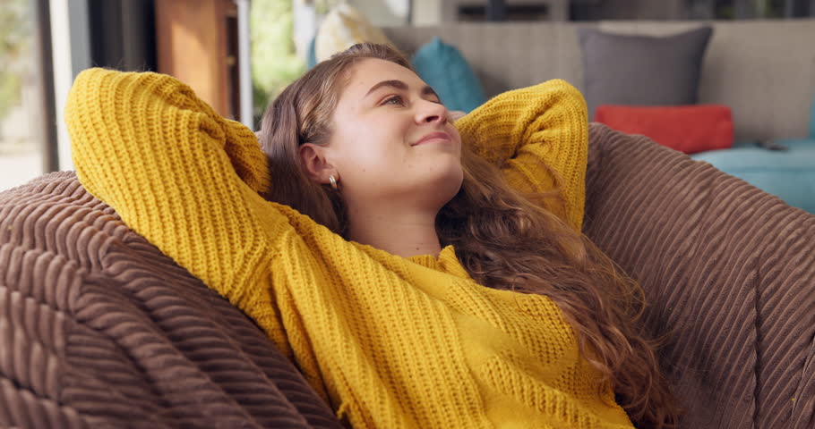 Girl, calm and happy in home for relax on weekend break for wellness, mental health and stress relief for wellbeing or self care. Woman, eyes closed and bean bag for sleep or comfort, peace and rest.