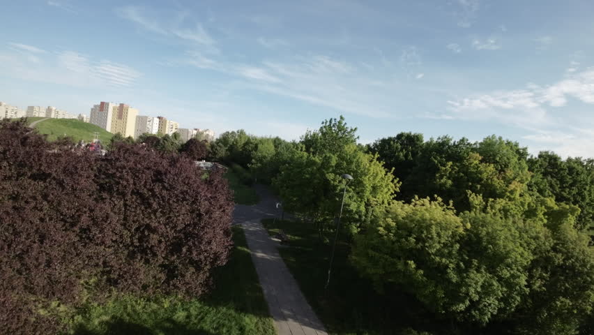 This video showcases a beautiful park with an abundance of green trees and grassy areas. It features a network of paved pathways that are perfect for walking, running, or biking. The park is located