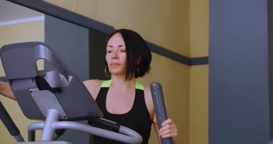 Caucasian woman woman exercising on step machine in fitness gym. Cardio exercise on a step machine. Physical education as a norm of life for maintaining health. Slow motion in 4k format.