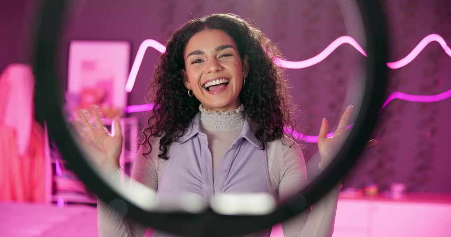 Young, woman and talking with ring light for vlog tutorial, influencer with neon in bedroom. Female person, discussion and review for live stream or podcast, content creator with broadcast in home
