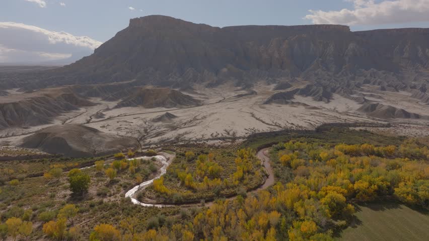 Aerial Forward Shot Of Stream In Semi Arid Desert By Sand Mountains Under Cloudy Sky - Moab, Utah