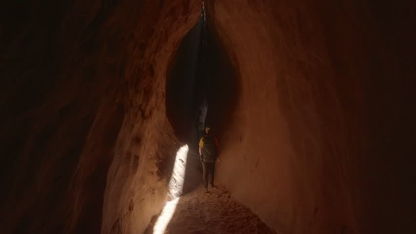 Aerial: Drone Forward Shot Of Male Tourist Walking In Cake At Famous State Park During Adventurous Vacation - Moab, Utah