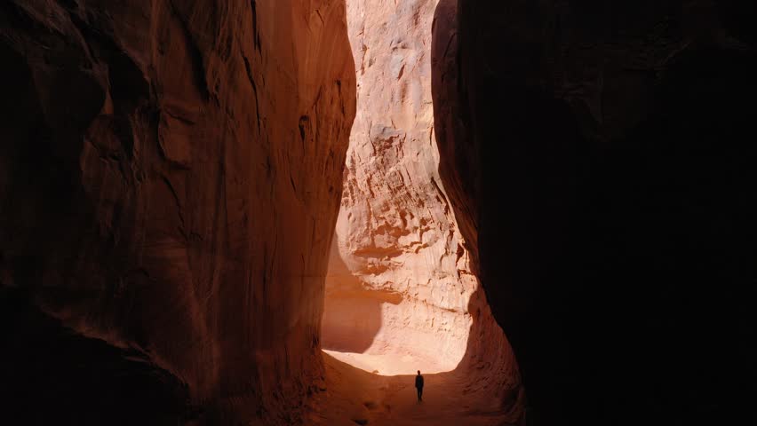Aerial: Drone Forward Shot Of Male Tourist Walking Amidst Rock Formations In Popular State Park During Vacation - Moab, Utah