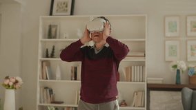 Asian mature retired Senior man wearing a vr headset adance and body humor moving around while looking around in virtual world in living room with hie wife cheering laugh healthy insurance lifestyle - Powered by Shutterstock - Get 15% off with code: PIKWIZARD15