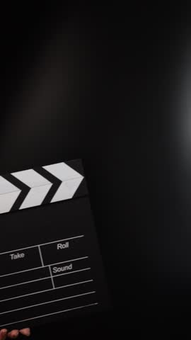 Hands with clapper board, cueing the action, movie production in progress.