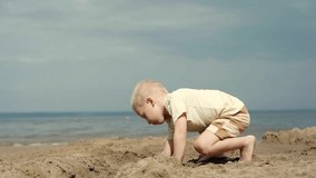 A young child plays on a sandy beach by the ocean, building a sandcastle. The sun is shining, and the child is having fun. Family weekend activities. Happy childhood - Powered by Shutterstock - Get 15% off with code: PIKWIZARD15