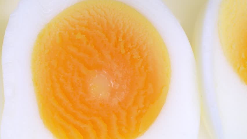 Close-up: Sliced boiled eggs, halves showcasing vibrant yolks encased in pristine whites. Yolks gleam softly, their texture invitingly smooth, adding allure to the wholesome simplicity.

