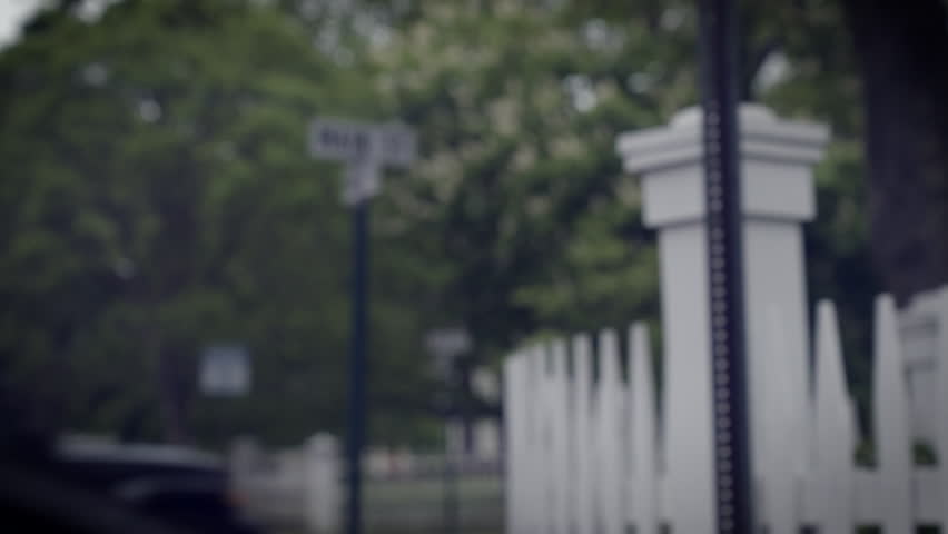 POV driving past a Main Street streetsign on a rainy day, two people walk past