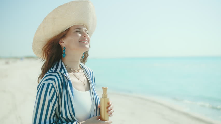 smiling elegant female on the seacoast with sunscreen.