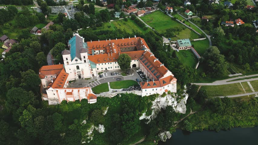 Aerial view of Benedictine abbey of Saints Peter and Paul in Tyniec, Poland. Panoramic view from drone of monastery courtyard, roofs and towers of stone buildings, green lawn of catholic church