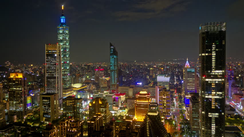 Aerial hyperlapse at night above Downtown Taipei, vibrant capital of Taiwan, with 101 Tower standing out among skyscrapers in XinYi Commercial District and city lights dazzling in the dark