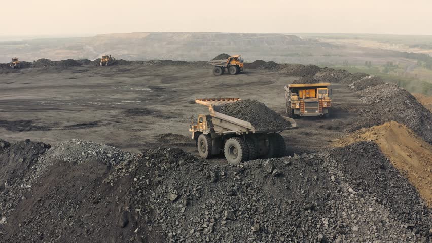 Large quarry dump truck. Loading rock in dumper. Loading coal into truck. Mining car machinery to transport coal. Open pit mine quarrying extractive industry stripping work. Big Yellow Mining Trucks