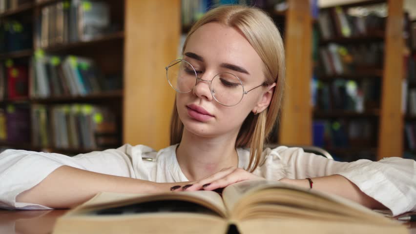 Close-up of a young girl student with a book in her hands. A sweet girl who is passionate about literature. Concept for exam preparation, scholarship and student life.