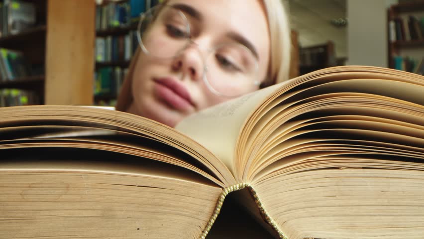 Close-up of a young girl student with a book in her hands. A sweet girl who is passionate about literature. Concept for exam preparation, scholarship and student life.