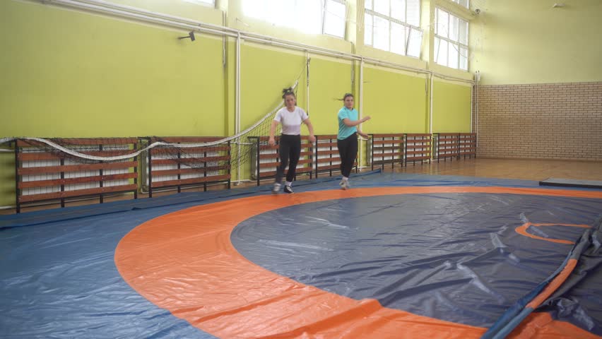 Multiracial female athletes warming up together. Female wrestling in the gym, training practice. Freestyle wrestling.