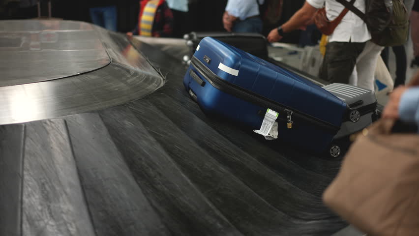 Many suitcases move conveyor belt. Lots of people wait baggage after arrival. Airport bags carousel. Hand luggage check in area. Train station travel. Tourist personal baggages. Busy queue. Fly trip.