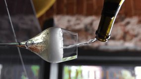hand pours sparkling wine into a glass in a restaurant. champagne with bubbles stands on the table in the restaurant. sparkling wine in a glass at a bar. vertical video - Powered by Shutterstock - Get 15% off with code: PIKWIZARD15