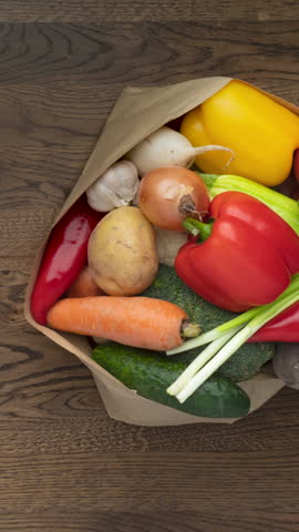 Fresh Vegetables Collecting Into paper bag on kitchen table, wooden background - stop motion animation, Nutrition, diet, vegan food concept, vertical footage