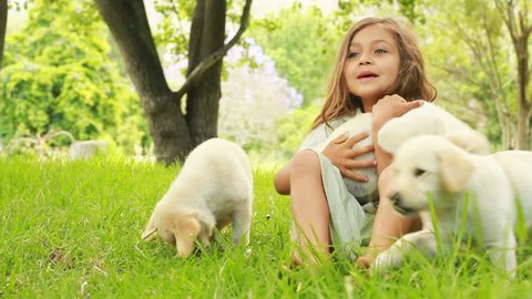 Innocent little girl playing with puppies in the garden.