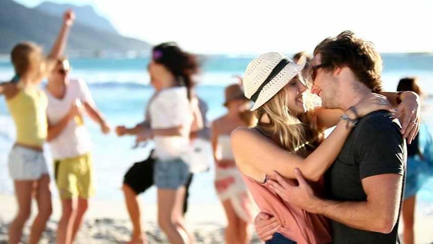 Hipster Friends having fun at the beach and a couple kissing in the front. 