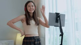 Asian women and beautiful bloggers wear headphones dancing videos by smartphone cameras. Creator vlogger talent dancing enjoys hobby content recording show video sharing on social media.