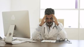 Stressed male doctor using computer and analyzing medical reports in clinic - Powered by Shutterstock - Get 15% off with code: PIKWIZARD15