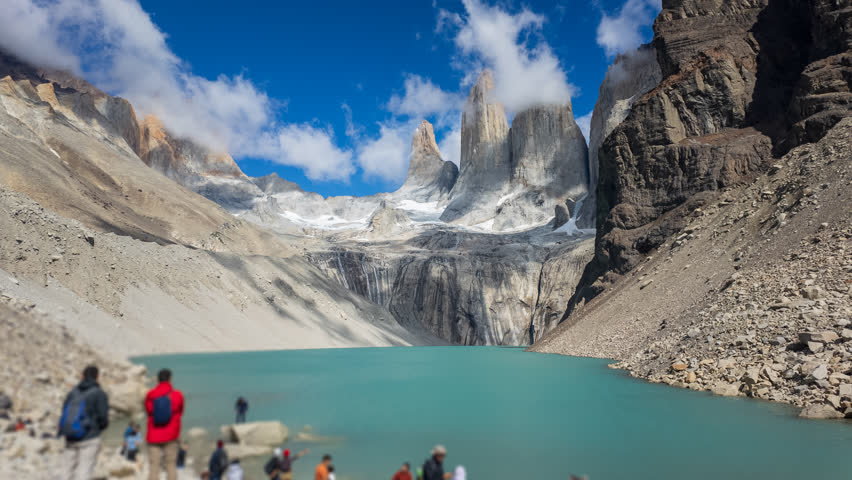 Time-lapse shows visitors enjoying the vibrant Torres del Paine with its green lake and peaks.