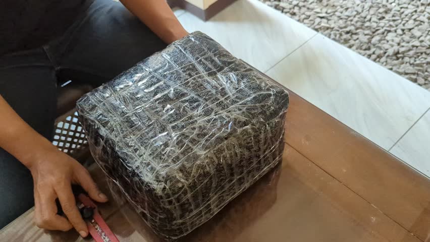 A male hand using sharp cutter knife slashing black box packing bubble wrap, in the wood table, unboxing of the e-commerce internet order box,4K.