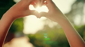 Kids palms form a symbol of heart, Child draws shape of heart with his fingers against sunset background. Little boy is playing with sun in park, looking at sky through symbol of heart. Family love. - Powered by Shutterstock - Get 15% off with code: PIKWIZARD15